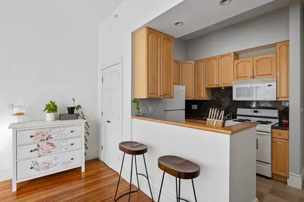 a kitchen with stainless steel appliances kitchen island granite countertop a refrigerator a stove a sink and white cabinets with wooden floor