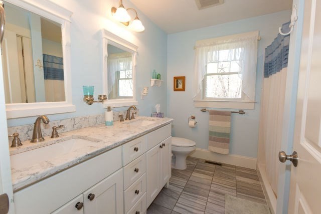 140 Warren Street Upton, MA 01568 - Photo 20 of 37 a bathroom with a granite countertop sink toilet a large mirror a vanity and next to a window