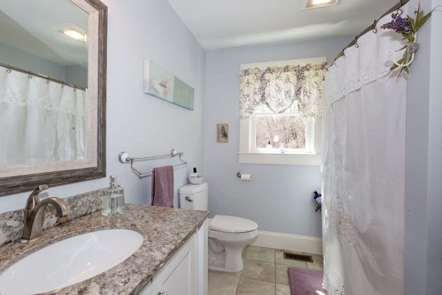 140 Warren Street Upton, MA 01568 - Photo 22 of 37 a bathroom with a granite countertop toilet a sink and a mirror