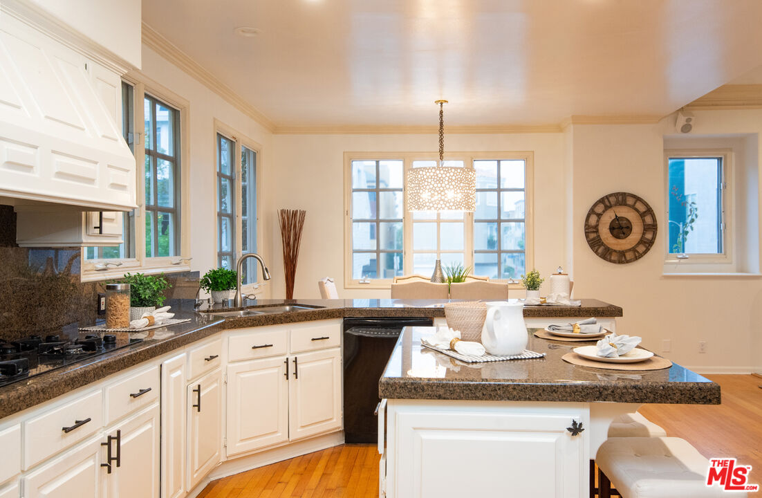 115 Roma Court Marina del Rey, CA 90292 - Photo 15 of 50 a kitchen with a sink dishwasher a stove and white cabinets with wooden floor
