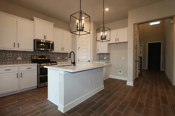 a view of kitchen with stainless steel appliances granite countertop refrigerator stove top oven and cabinets