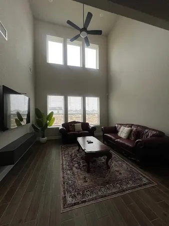an empty room with windows and chandelier fan