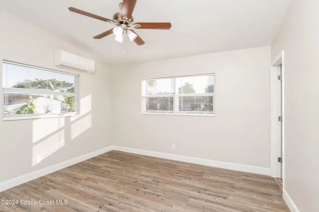 a view of an empty room with a window and wooden floor