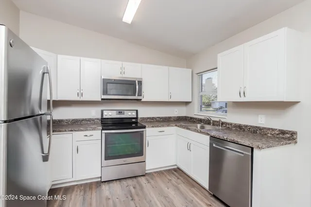 a kitchen with granite countertop a sink stove and refrigerator