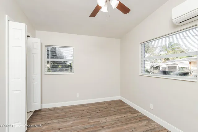 a view of an empty room with wooden floor and window