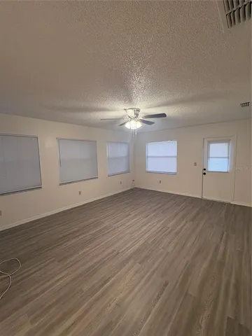 an empty room with wooden floor and windows