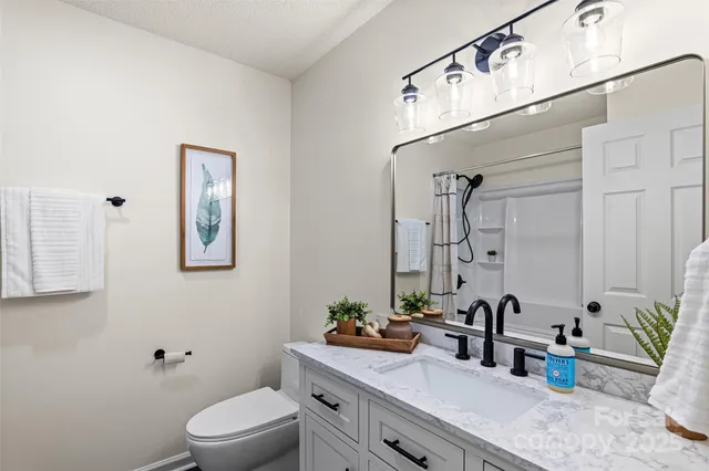 a bathroom with a granite countertop sink a toilet and mirror