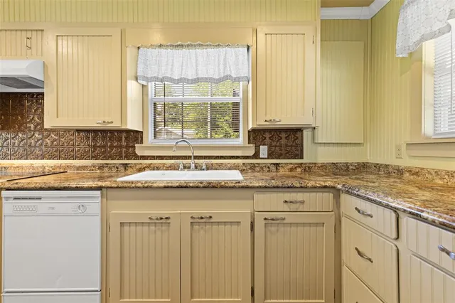 a kitchen with granite countertop white cabinets and sink