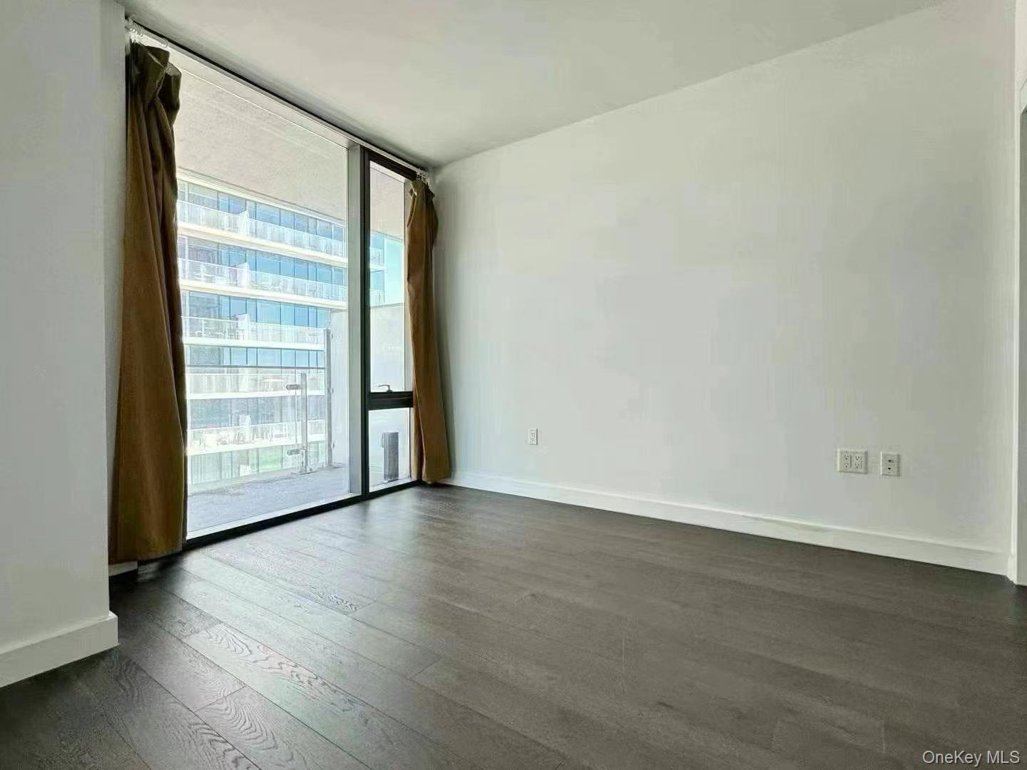 131-03 40 Road, Unit 16D Queens, NY 11354 - Photo 4 of 10 a view of an empty room with wooden floor and a window