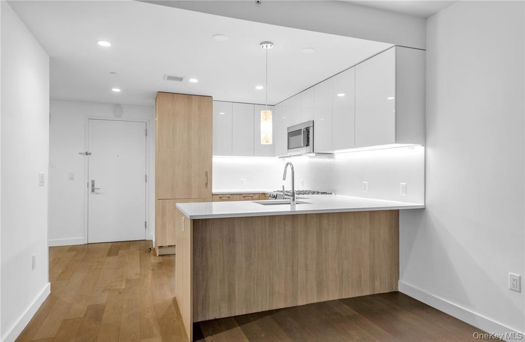 131-03 40 Road, Unit 16D Queens, NY 11354 - Photo 5 of 16 a kitchen with kitchen island a sink stainless steel appliances and cabinets