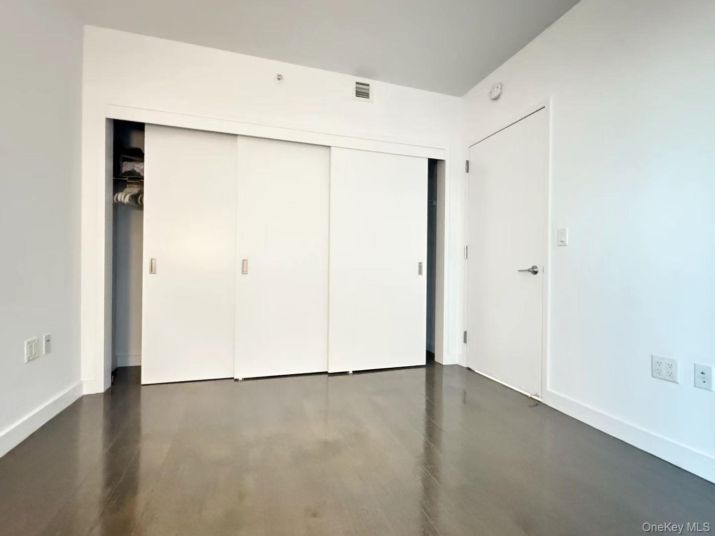 131-03 40 Road, Unit 16D Queens, NY 11354 - Photo 6 of 10 an empty room with wooden floor and a window