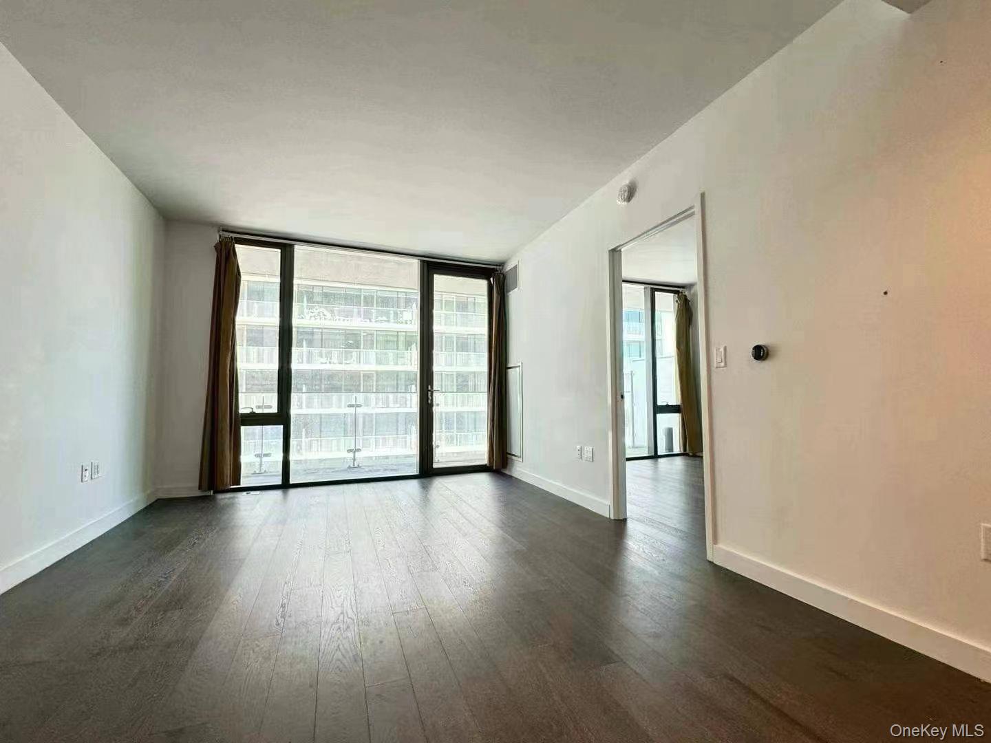 131-03 40 Road, Unit 16D Queens, NY 11354 - Photo 7 of 10 wooden floor in an empty room with a window