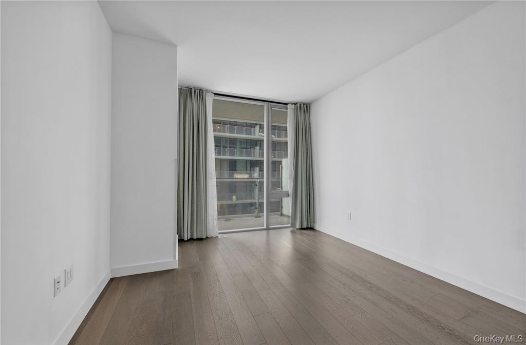 131-03 40 Road, Unit 16D Queens, NY 11354 - Photo 8 of 16 an empty room with wooden floor and empty shelves
