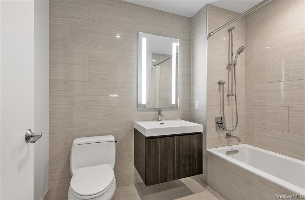 131-03 40 Road, Unit 16D Queens, NY 11354 - Photo 10 of 16 a bathroom with a toilet a sink a mirror a bathtub and shower