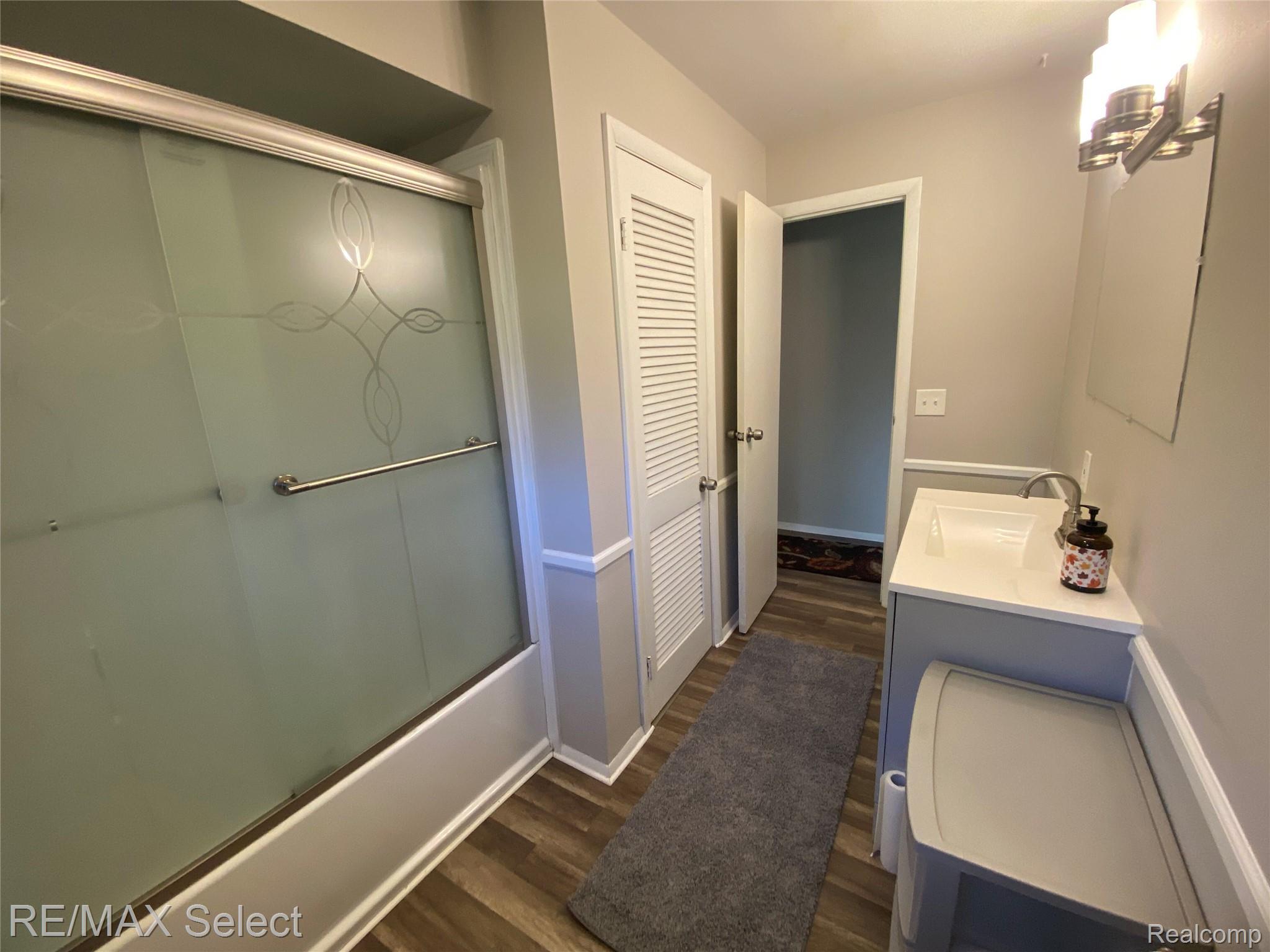 6169 Johnson Road Flushing, MI 48433 - Photo 15 of 28 Bathroom featuring enclosed tub / shower combo, vanity, and dark wood-style flooring