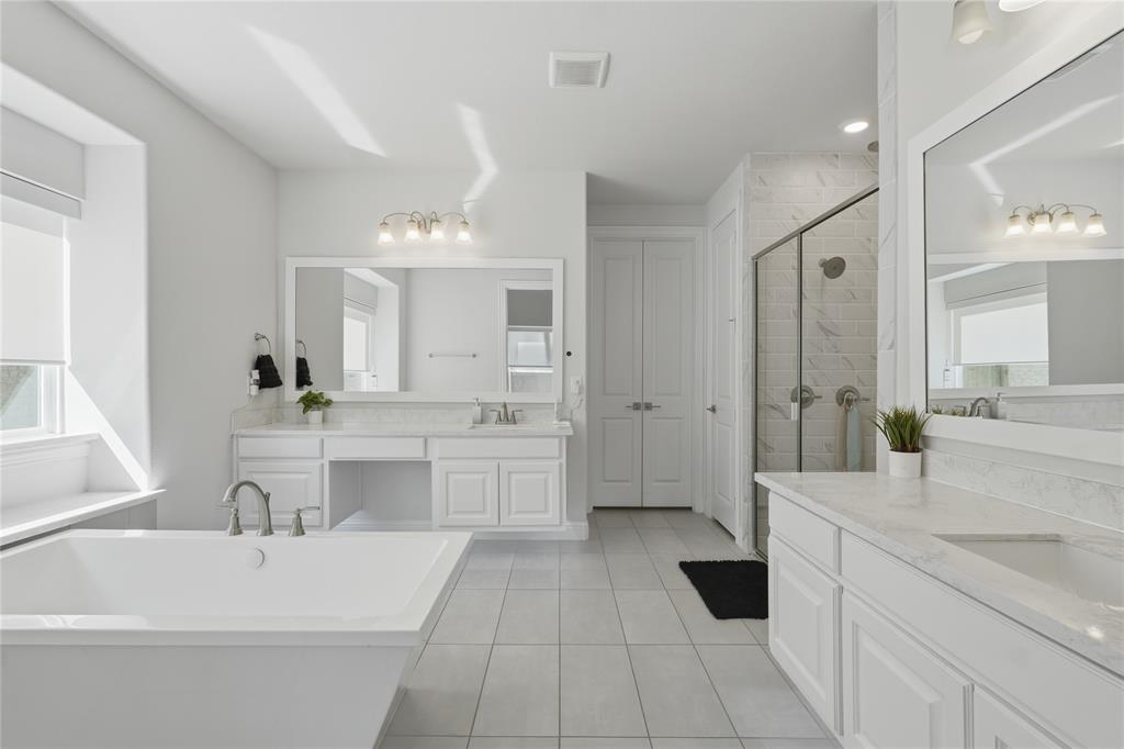 7548 Ridge Lane Grand Prairie, TX 75054 - Photo 19 of 35 Bathroom featuring two vanities, a shower stall, a freestanding tub, and light tile patterned floors