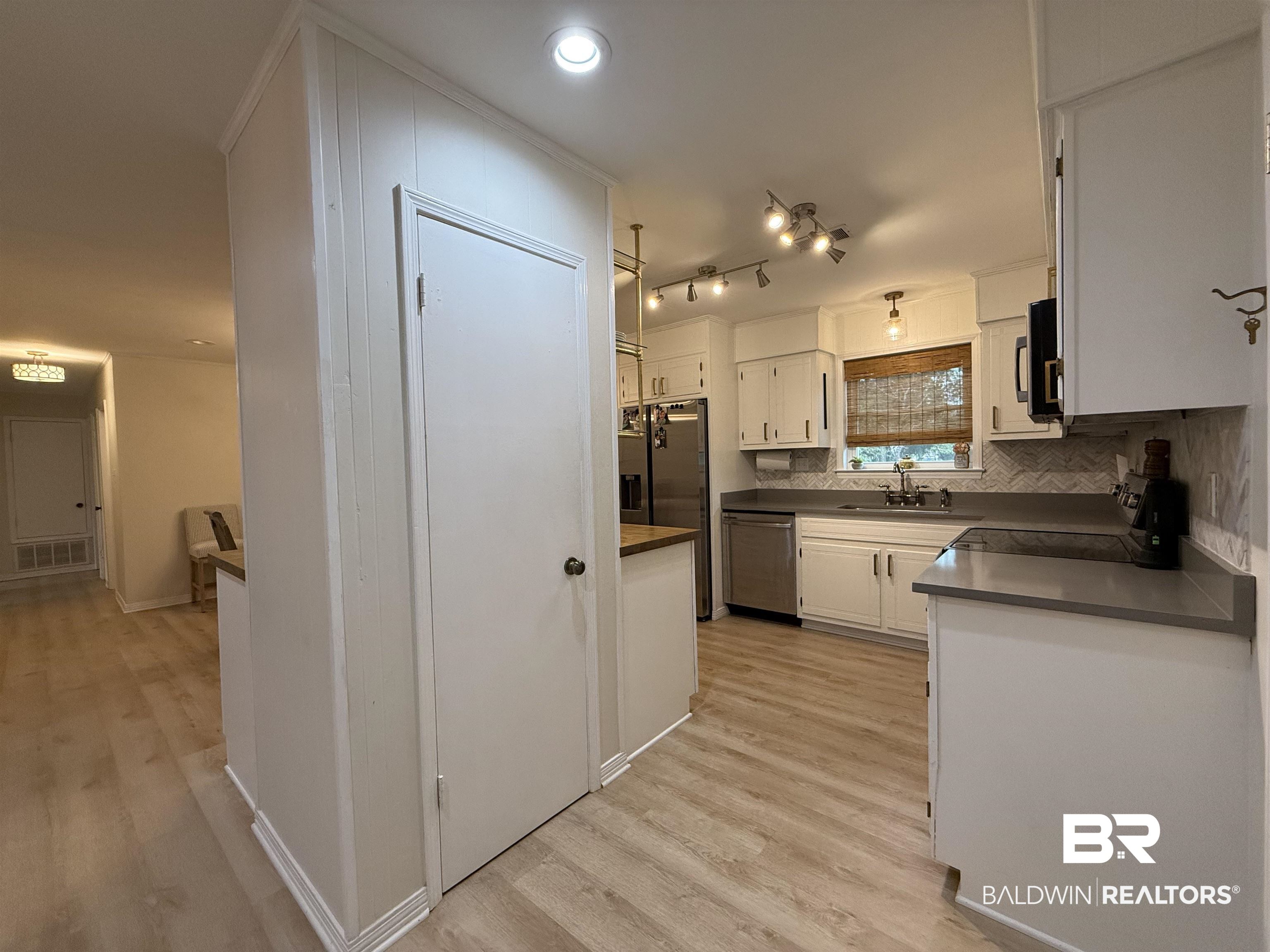 90 Florida Street Monroeville, AL 36460 - Photo 14 of 31 Kitchen with tasteful backsplash, appliances with stainless steel finishes, sink, light wood-type flooring, and white cabinetry