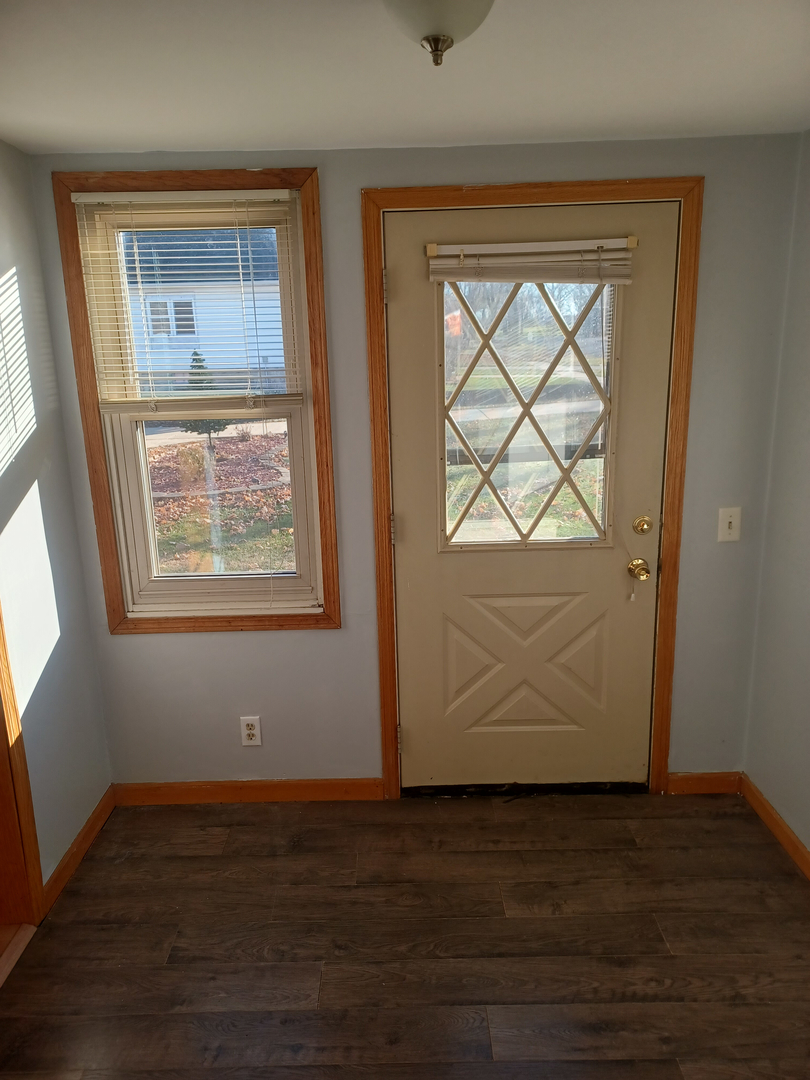 206 South Stott Street Genoa, IL 60135 - Photo 3 of 18 an empty room with wooden floor and windows