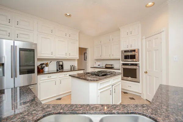 a kitchen with stainless steel appliances granite countertop a stove a sink and a refrigerator