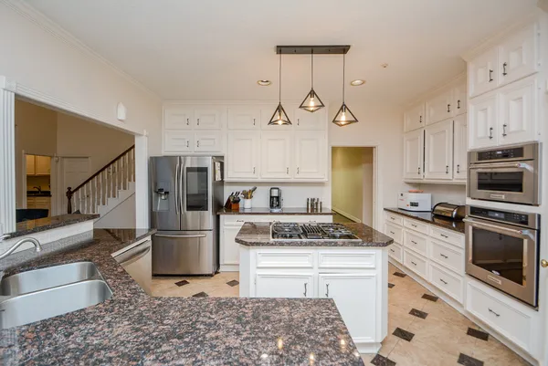a kitchen with stainless steel appliances granite countertop a stove a sink and a refrigerator