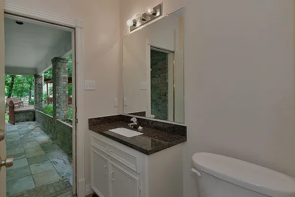 a bathroom with a granite countertop sink and a toilet