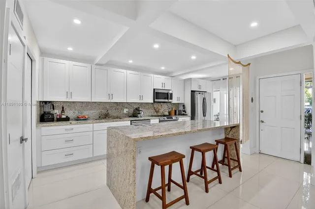 a kitchen with stainless steel appliances granite countertop white cabinets a sink stove and refrigerator