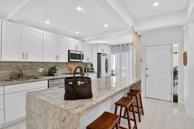 a kitchen with stainless steel appliances granite countertop a refrigerator a stove a sink a dining table and chairs