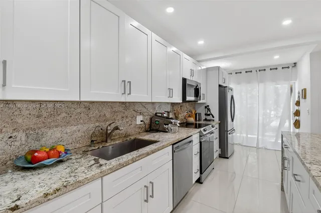 a kitchen with stainless steel appliances granite countertop white cabinets a stove a sink and dishwasher