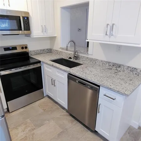 a kitchen with granite countertop a sink dishwasher a stove and a microwave oven on granite countertops