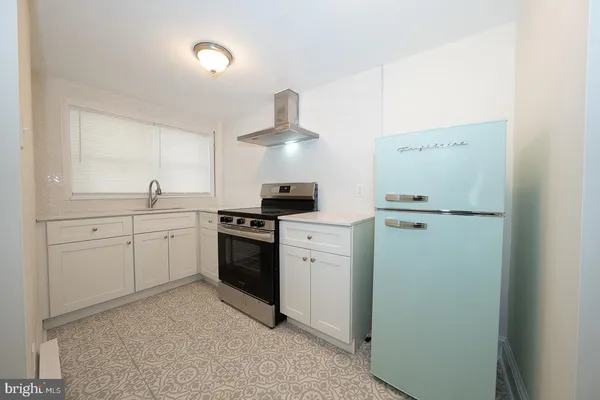 a view of a small house with a big yard and large tree
