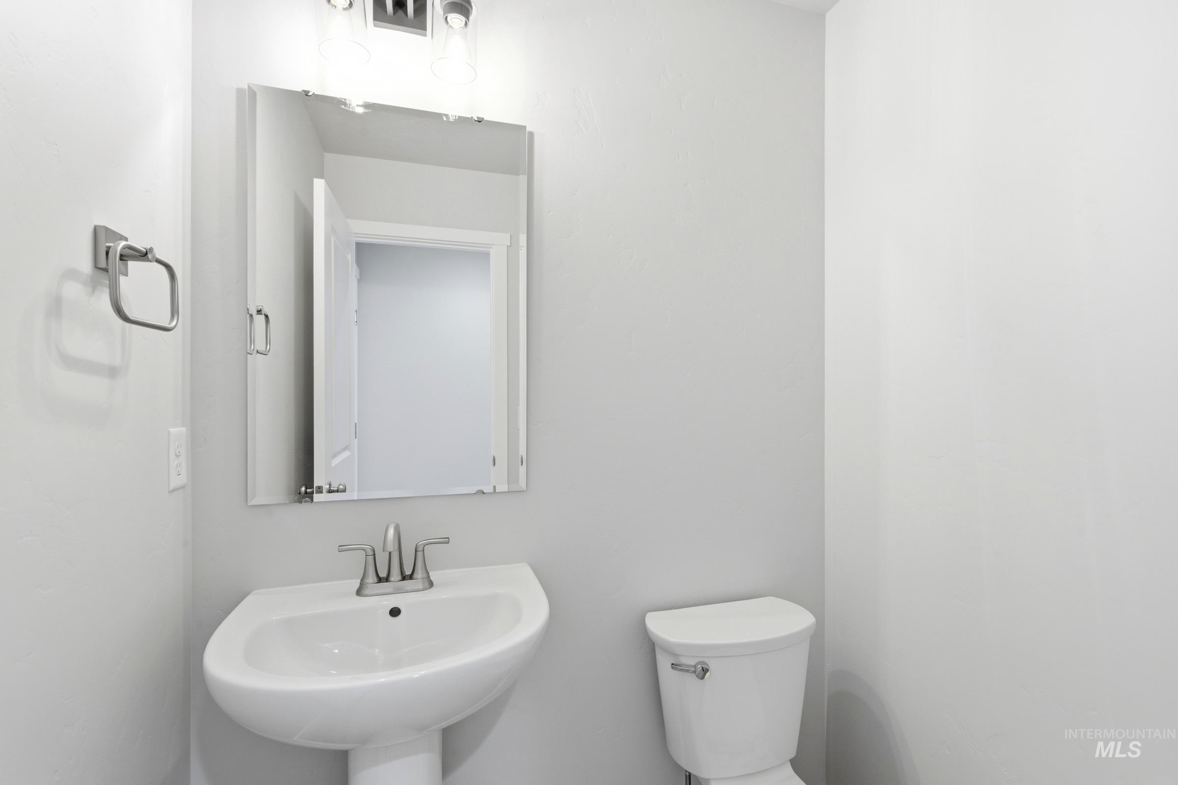 13709 Redway Court Caldwell, ID 83607 - Photo 12 of 28 Pedestal sink featuring a chrome faucet, wall-mounted mirror, and overhead vanity lighting