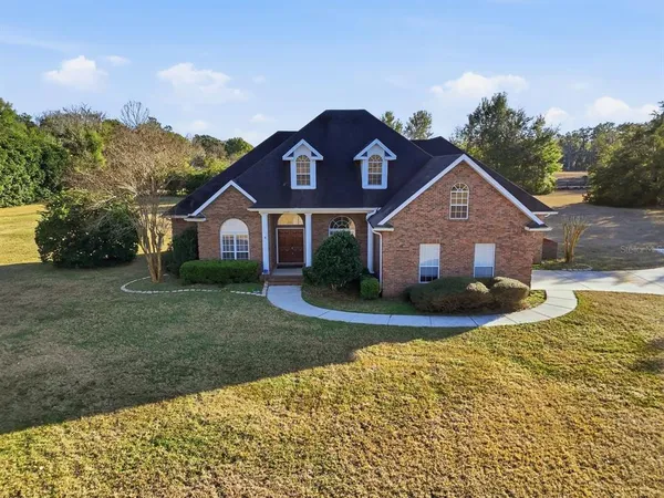 a view of a big house with a big yard and large tree