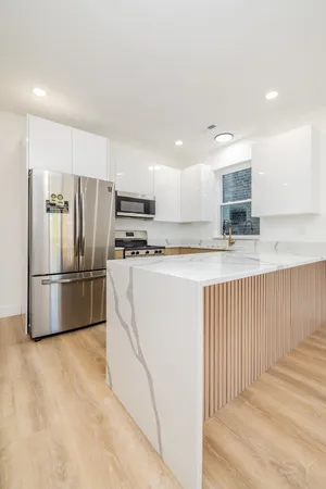 a view of a refrigerator in kitchen and white cabinets