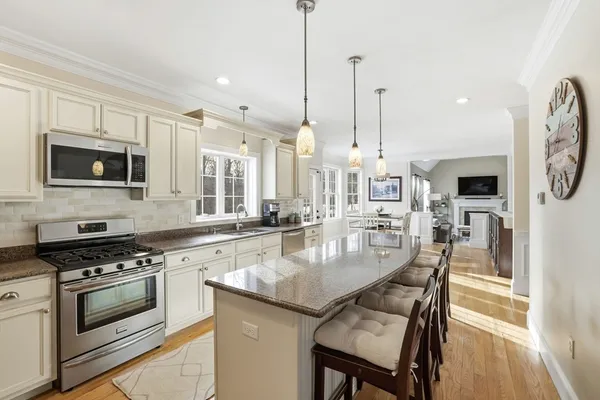 a large kitchen with stainless steel appliances granite countertop a stove a sink dishwasher a dining table and chairs with wooden floor