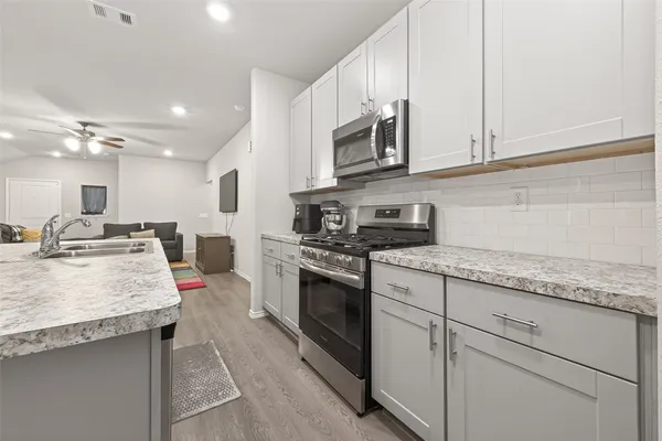 a kitchen with stainless steel appliances granite countertop a sink stove and microwave