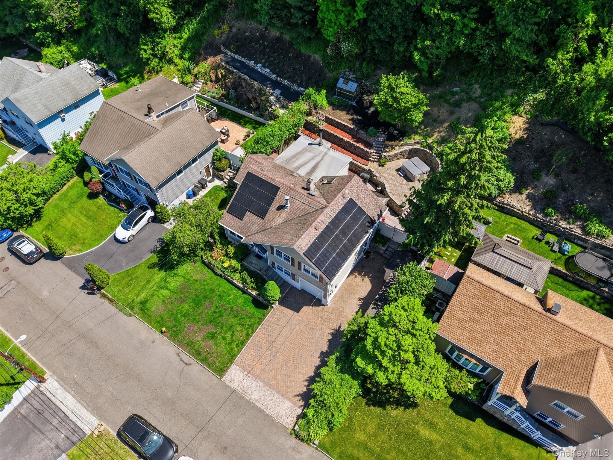 29 Montrose Road Yonkers, NY 10710 - Photo 33 of 39 Property featuring solar panels, a multi-level terraced backyard, mature trees, a paved driveway, and manicured lawns
