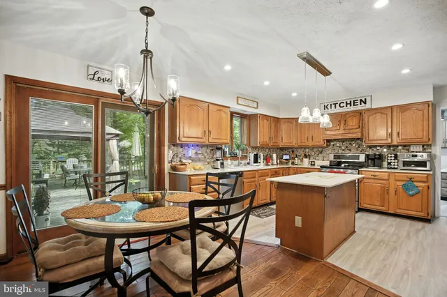 a kitchen with stainless steel appliances granite countertop a stove a sink dishwasher and a refrigerator with wooden floor