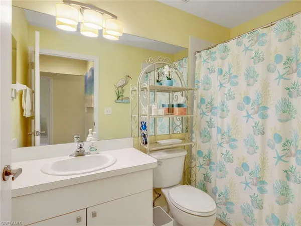 a bathroom with a sink a toilet a mirror a vanity and shower curtain