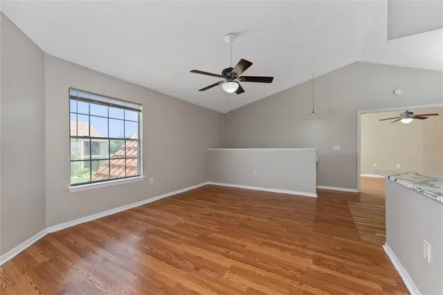 a view of an empty room with a window and a kitchen