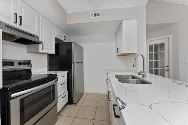 a kitchen with granite countertop a sink stove and refrigerator