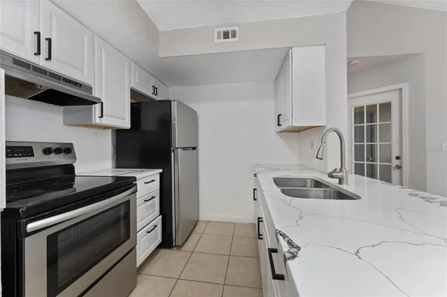 a kitchen with granite countertop a sink stove and refrigerator