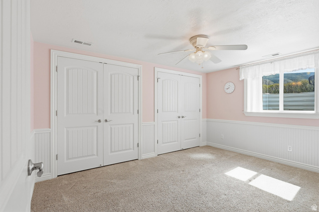 2420 West Old Hwy Road Morgan, UT 84050 - Photo 37 of 54 Unfurnished bedroom with a wainscoted wall, two closets, carpet flooring, and a ceiling fan