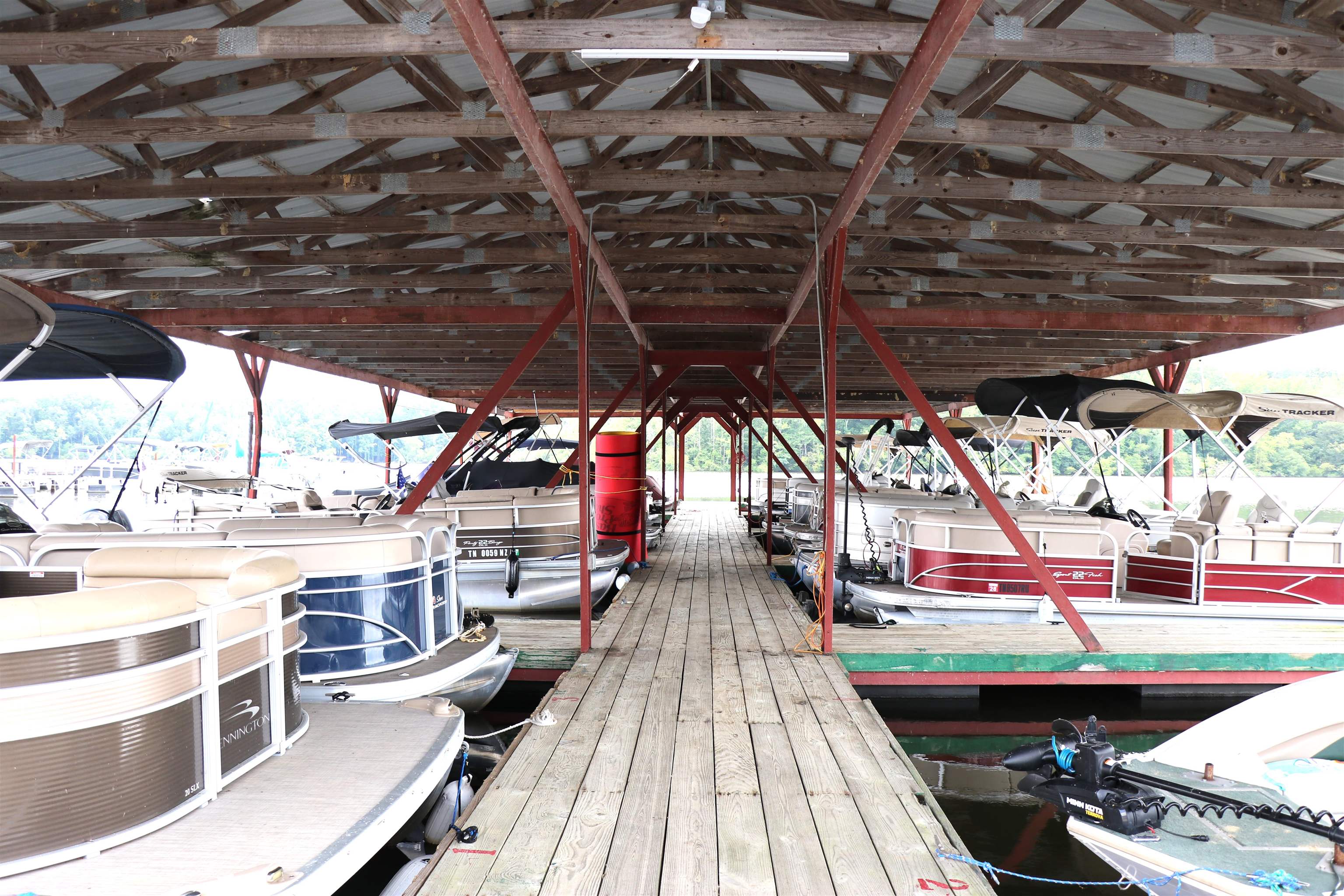 160 Patrick Drive Springville, TN 38256 - Photo 22 of 34 Covered boat dock featuring a central wooden walkway, exposed wooden rafters, and metal support beams