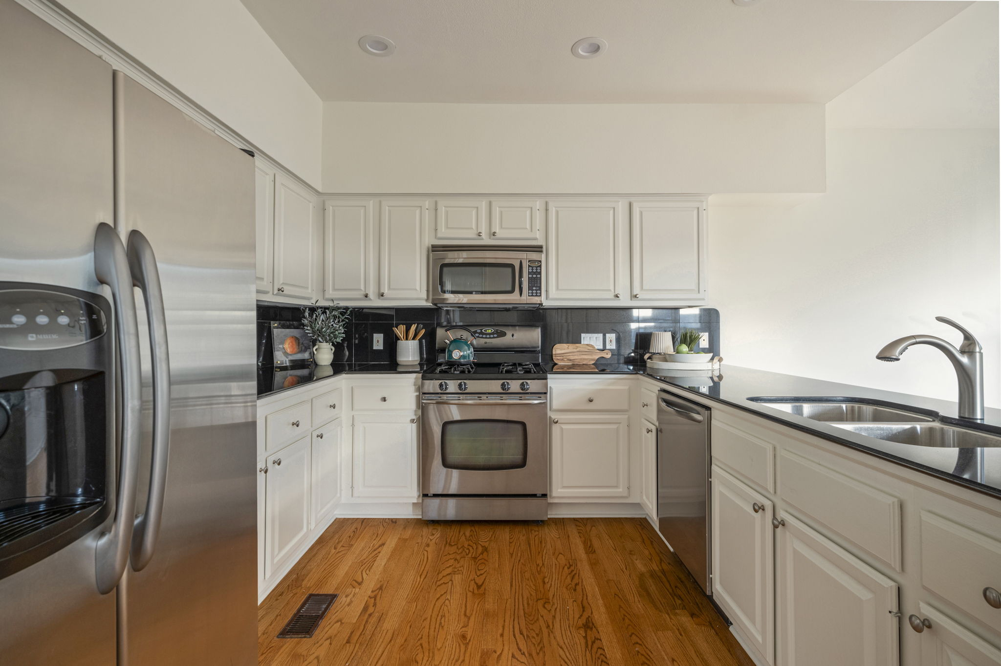6010 Long Champ Court, Unit 113 Austin, TX 78746 - Photo 13 of 25 Kitchen with stainless steel appliances, light wood-type flooring, white cabinetry, tasteful backsplash, and recessed lighting