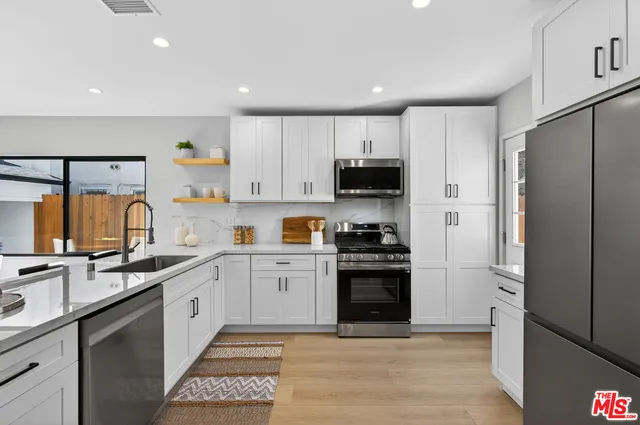 a kitchen with stainless steel appliances a stove refrigerator sink and cabinets