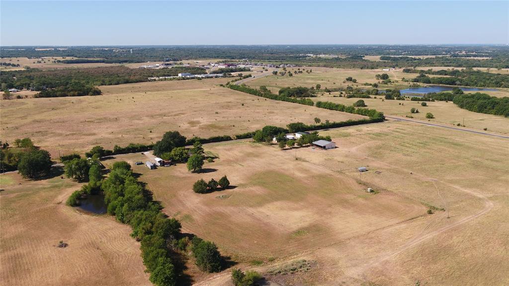Expansive acreage featuring multiple structures, open fields, and a private pond
