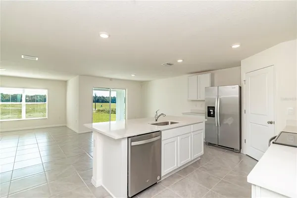 a kitchen with a sink white cabinets and refrigerator