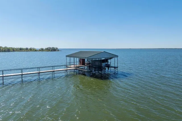 a view of a lake with table and chairs under an umbrella