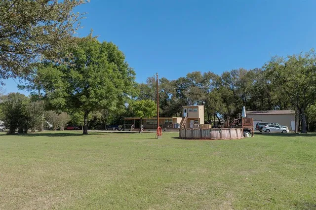 a view of a park with large trees and a wooden fence