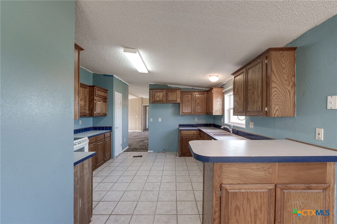 809 Crest Court Copperas Cove, TX 76522 - Photo 10 of 22 a kitchen with kitchen island granite countertop a sink and a refrigerator